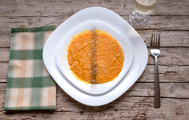 Pumpkin risotto with parmesan, black pepper and olive oil on old wooden background. Top view