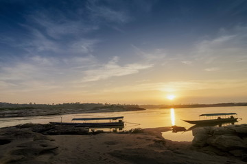 view morning of long boats floating in Mekong river with yellow sun light in the sky background, sunrise at Sam Phan Bok, Ubon Ratchathani, Thailand.