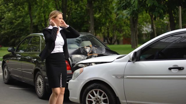 Frustrated woman observing car damage after rear-end collision on parking lot