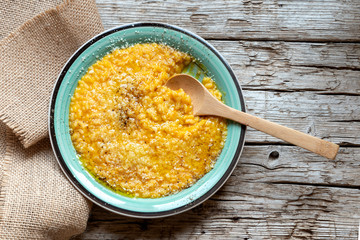 Pumpkin risotto with parmesan, black pepper and olive oil on old wooden background. Top view