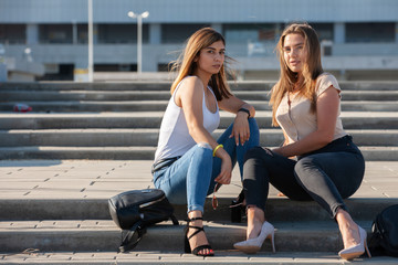 Beautiful girls in a city. Stylish ladies sitting on a stairs