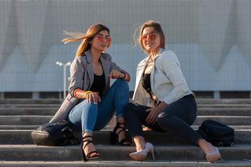 Fototapeta premium Beautiful girls in a city. Stylish ladies sitting on a stairs