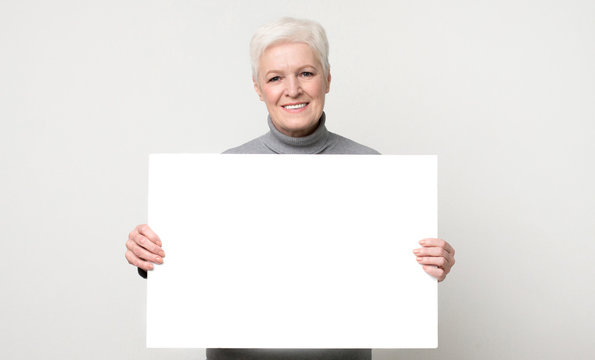 Beautiful aged woman posing with white empty board