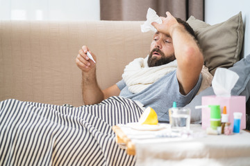 High temperature concept. Man feels badly ill. How to bring fever down. Cold symptoms and causes. Sick man with flu. Man hold thermometer. Measure temperature. Break fever remedies.