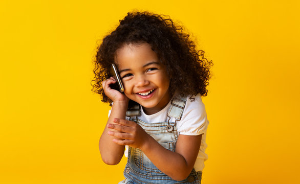 Cute afro girl talking on cellphone on yellow background