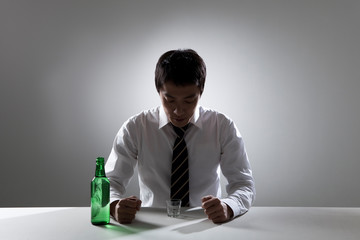 Image of a businessman drinking alcohol by himself.