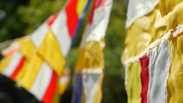 Buddhist prayer flags swaying in the wind in the rays of the rising sun in a temple. Closeup Slow Motion Footage. Shallow depth of field