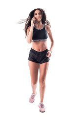 Fototapeta premium Multitasking. Young active woman jogger in sporty clothes running and talking on cellphone. Full body isolated on white background. 