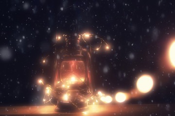 Christmas burning lantern with snowfall at night. Closeup view