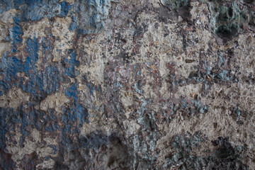 damaged concrete wall with traces of paint. The traces of paint are mostly blue, green and brown