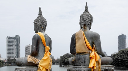 Yellow sashes on Buddhist figures and the skyline of Colombo