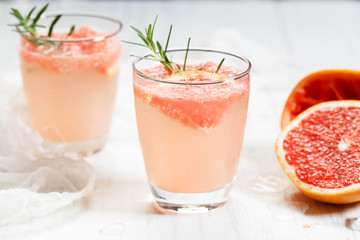 Glass of grapefruit drink with ice and rosemary