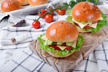 Sandwich with ham, cucumbers, tomatoes, lettuce leaves and cheese on wooden board
