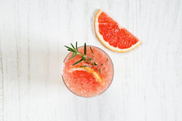 Glass of grapefruit drink with ice and rosemary