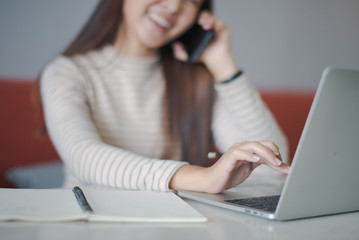 Focus on hand of young Asian woman using a notebook laptop which put on the table and other hand...