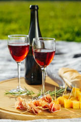 picnic in nature a light meal under wine, on a wooden background two glasses of red wine