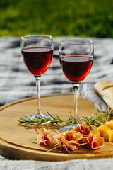 picnic in nature a light meal under wine, on a wooden background two glasses of red wine