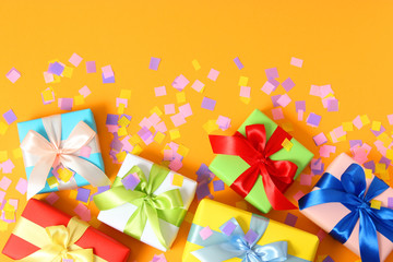 gifts and confetti on a colored background top view. Holiday giving gifts