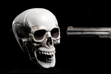 Kill Death, skull pointed by a weapon. With copy space text. Studio Shot. Isolated on black background.