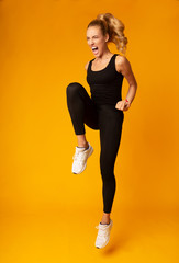 Skinny Girl Jumping Expressing Aggression Over Yellow Studio Background