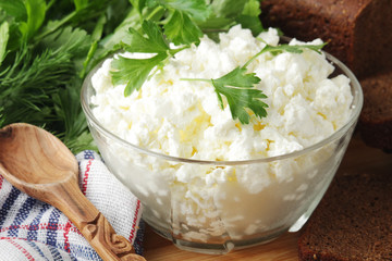 A bowl with cottage cheese, a bunch of green and rye bread