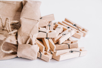 Wooden clothespins in paper bag with rope on white background. View from above. Place for your text