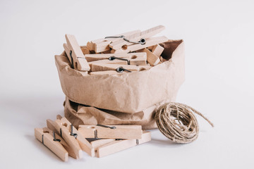 Wooden clothespins in paper bag with rope on white background. Place for your text