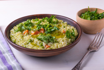 Classic Italian risotto with peas and fried bacon on a clay rustic plate