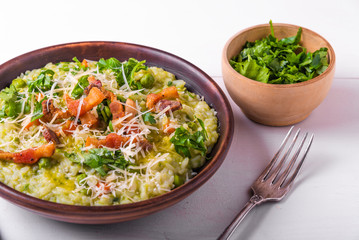 Classic Italian risotto with peas and fried bacon on a clay rustic plate