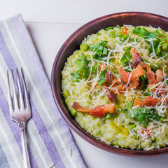 Classic Italian risotto with peas and fried bacon on a clay rustic plate