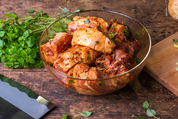 The meat is pickled in a glass bowl on a rustic wooden table, ingredients for cooking traditional Asian meat dishes and a Chinese kitchen knife