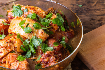 Slices of pork with ribs marinated in spicy sauce with basil in a glass bowl close-up