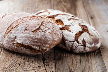 Gold rustic crusty loaves of bread and buns on wooden background. Still life captured from above top view, flat lay.