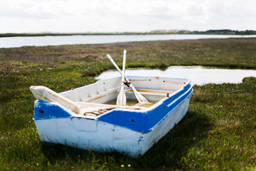 A beached row boat on green grassy marsh land in Orford, Suffolk