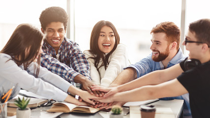 Successful teamwork. Students putting their hands together