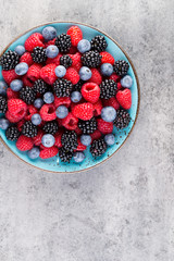 Fresh berry salad on blue dishes. Vintage wooden background.