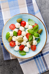 Delicious caprese salad with ripe cherry tomatoes and mini mozzarella cheese balls with fresh basil leaves.