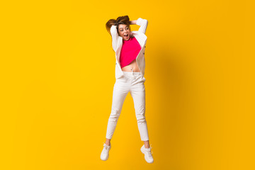 Young woman jumping over isolated yellow wall