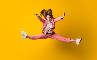 Obraz premium Young woman jumping over isolated yellow wall