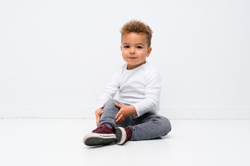 kid over isolated white background sitting on the floor
