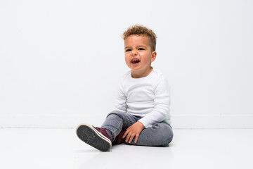 kid over isolated white background sitting on the floor