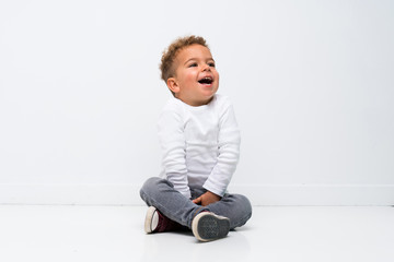 Happy kid over isolated white background sitting on the floor
