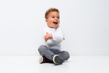 Happy kid over isolated white background sitting on the floor