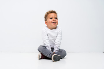 Happy kid over isolated white background sitting on the floor