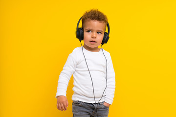 kid over isolated yellow background listening music