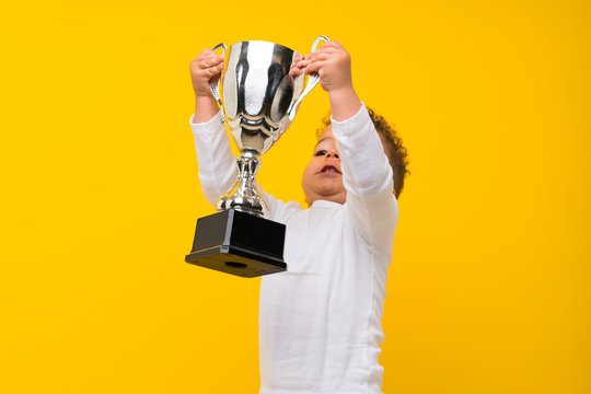 Kid Over Isolated Purple Background Holding A Trophy