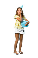 A full-length shot of a Little girl at a birthday party holding a gift is a little bit nervous and scared on isolated white background