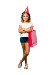 Obraz na płótnie Canvas A full-length shot of a Little girl at a birthday party holding a gift bag keeping arms crossed on isolated white background