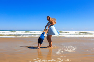 Naklejka premium Mother and daughter are spinning on the beach at sunny day.