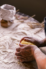 Female hands and dough. A woman is preparing a dough for home baking. Rustic style photo. Wooden table, wheat ears and flour. Free space for text